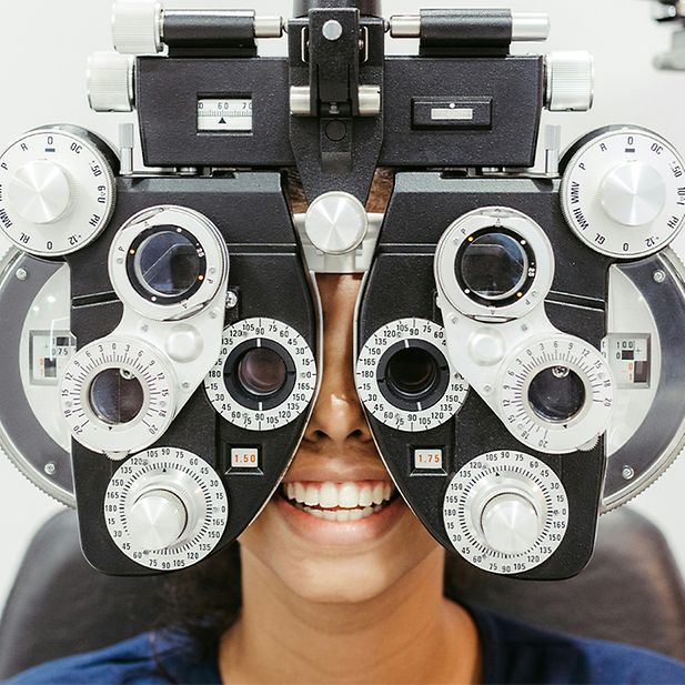 Een vrouw lacht terwijl ze een oogonderzoek doet