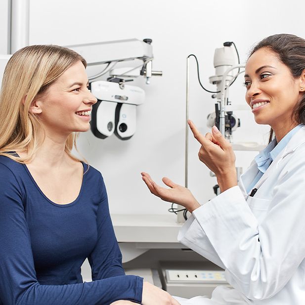 Un ophtalmologue conseille une patiente. La patiente sourit. 