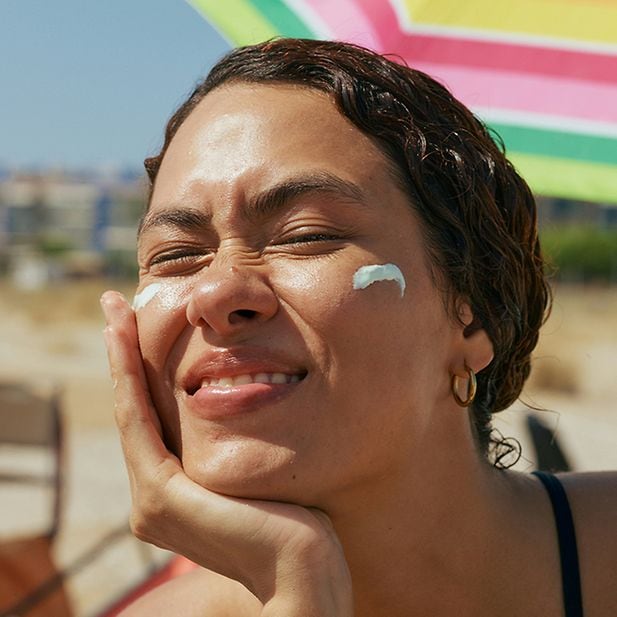 Vrouw brengt zonnebrandcrème aan op haar gezicht op een zonnige dag