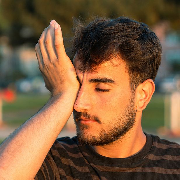Man wrijft in zijn oog met de palm van zijn hand en lijkt geïrriteerd