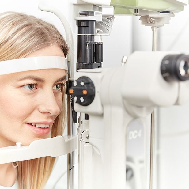 Een vrouw kijkt in een optometer in een optometriepraktijk.