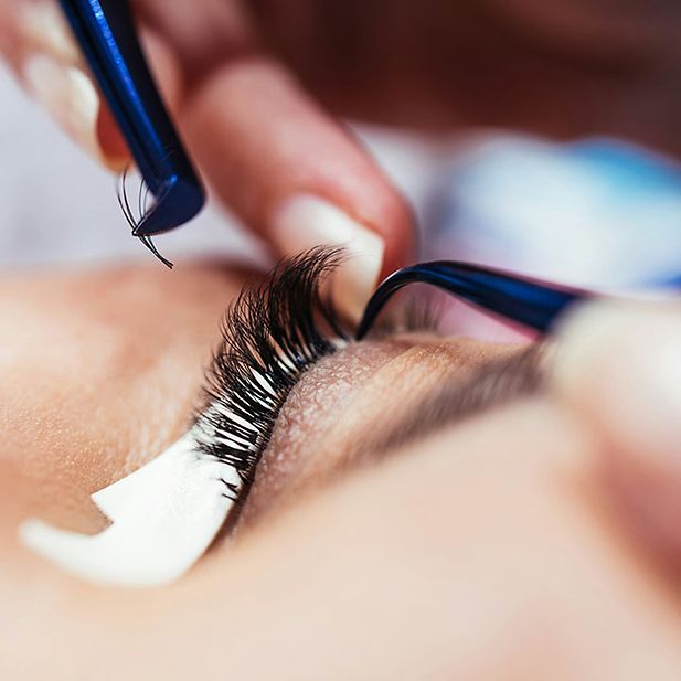 Close-up van een schoonheidsspecialist die wimperextensions aanbrengt met een pincet