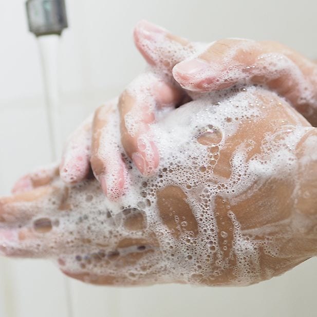 Handen die worden met zeep worden gewassen onder een kraan