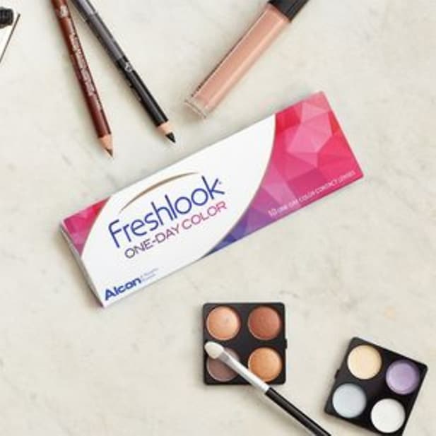 Een doosje Freshlook One-Day Colour kleurlenzen naast oogschaduwpaletten, oogpotloden en concealer.