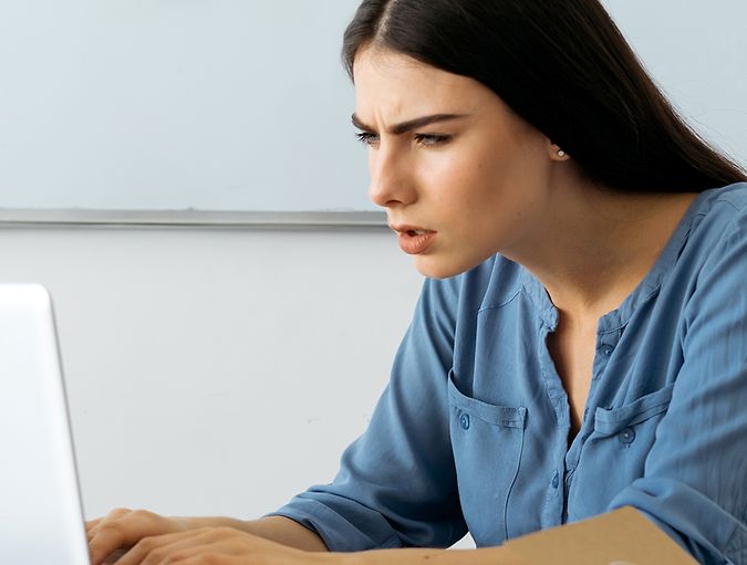 Vrouw knijpt haar ogen samen terwijl ze naar haar laptop kijkt
