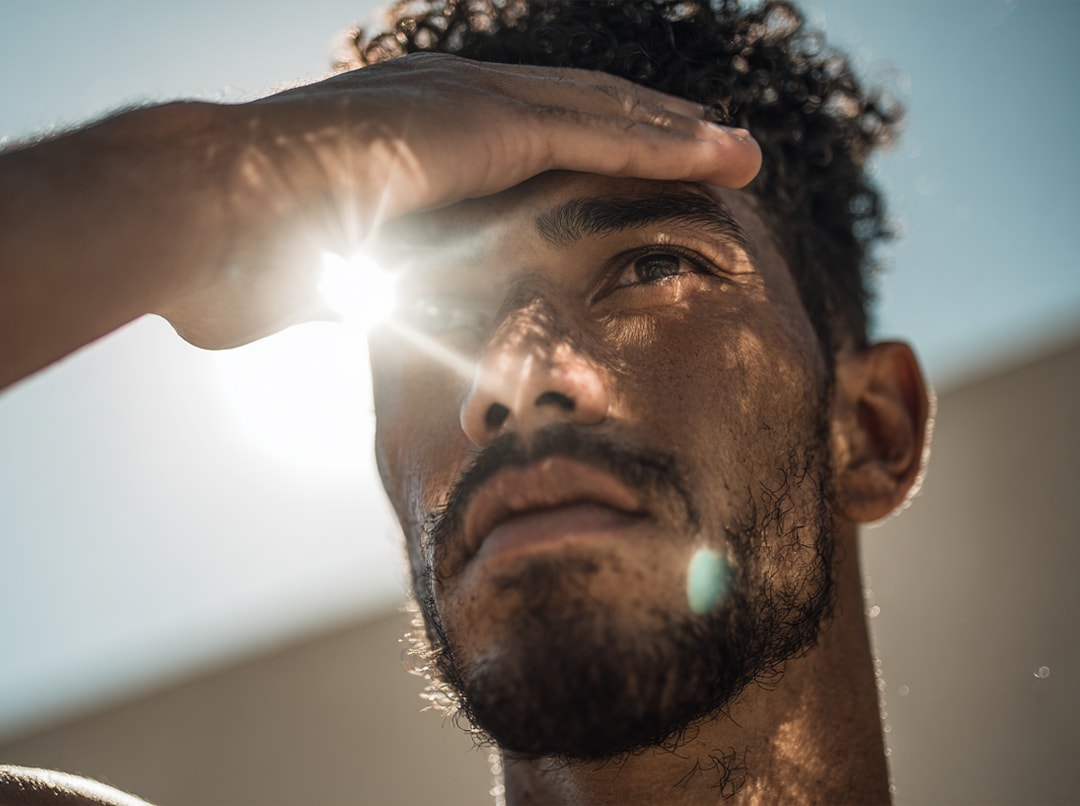 Man houdt zijn hand boven zijn ogen tegen fel zonlicht